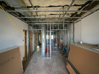 Hallway with metal wall framing and stacked drywall sheets during a rebuild